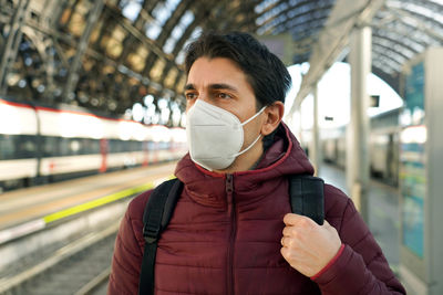 Man wearing mask standing on railroad station