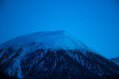 Low angle view of snowcapped mountains against clear blue sky