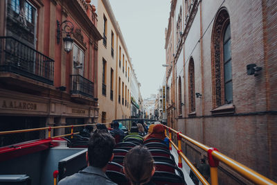 Rear view of people walking on canal amidst buildings in city