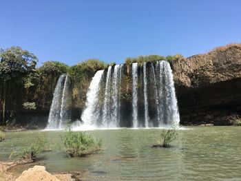 Scenic view of waterfall against sky