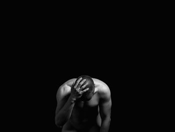 Rear view of shirtless man against black background