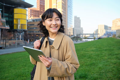 Portrait of young woman standing against buildings