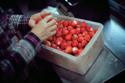 Midsection of man selling strawberries at market stall during night