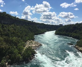 Scenic view of river flowing in forest against sky