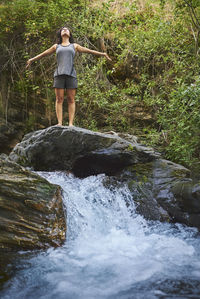 Young woman practicing yoga in a river. she's in the middle of nature.