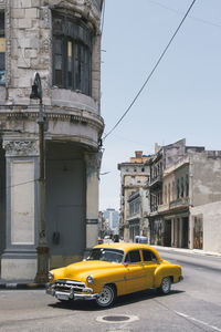 Cuba, havana, yellow vintage car driving along street in centro habana