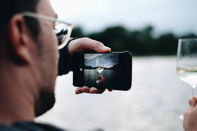 Man photographing wineglass through mobile phone