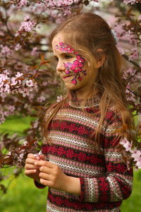 Spring portrait of a six year old girl standing under the blooming pink cherry tree