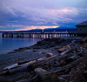 Pier on sea against cloudy sky