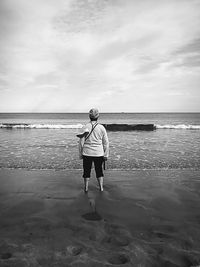 Rear view of man on beach against sky