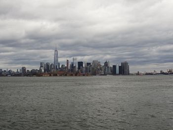 Sea and buildings in city against sky