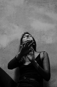 Portrait of young woman standing against wall