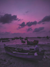 Boats moored on sea against sky at sunset