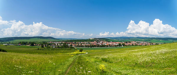 Panoramic view of field and buildings against sky