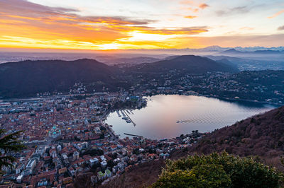 The city of como and the lake, photographed from brunate, at dusk, and mountains in the background.