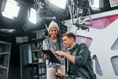 Young man is preparing for tv online broadcast. woman helps with make up.