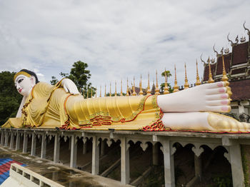 Statue by temple against sky