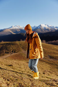 Rear view of woman walking on mountain against clear sky