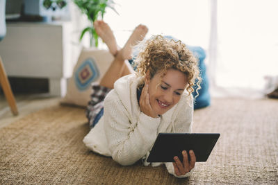 Portrait of young woman using mobile phone while sitting on bed at home