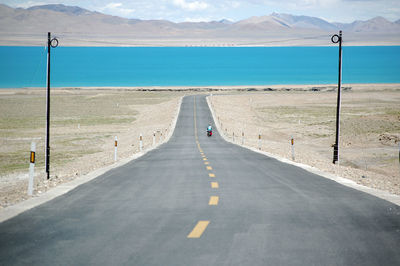 A flat straight road leads to the blue lake