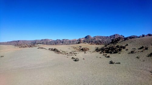 Scenic view of desert against clear blue sky