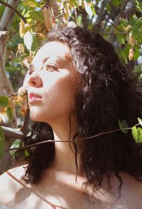 Young woman looking away against trees