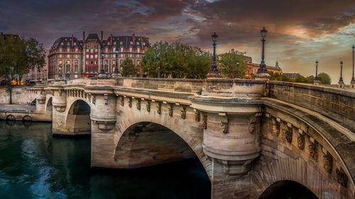 Arch bridge over river against cloudy sky