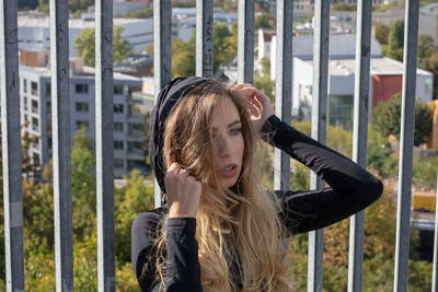 Thoughtful beautiful woman with blond hair by fence