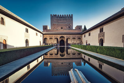 View of an interior basin of the alhambra palace in granada reflecting the walls of the palace
