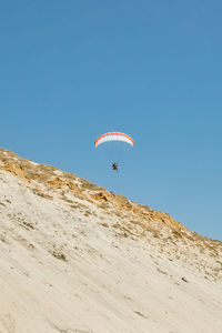 Young man paragliding during sunset off cliffs in baja, mexico.