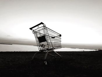 Side view of abandoned shopping cart on field against sky