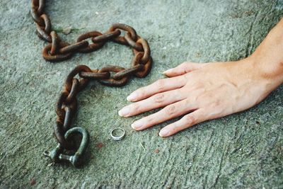 High angle view of person hand by ring and chain