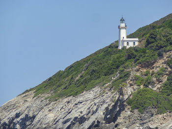 Low angle view of building by mountain against clear sky