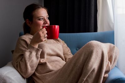 Young woman drinking coffee on bed at home