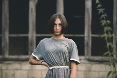 Beautiful young woman looking away while standing against windows