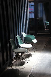Empty chairs and table against wall in building
