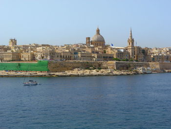 View of buildings by sea against clear sky