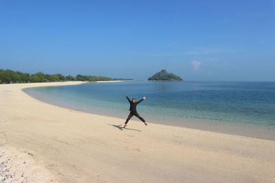 Man with arms raised jumping at beach