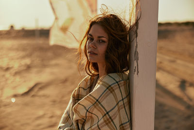 Portrait of young woman looking away while standing on field