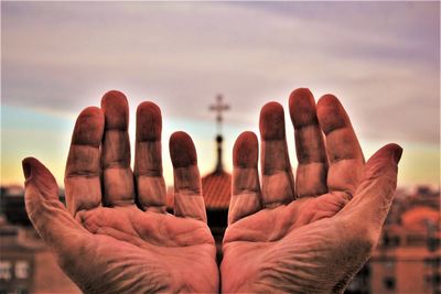 Close-up of human hand against sky