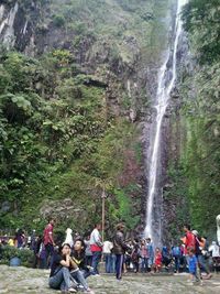 People standing by waterfall in forest