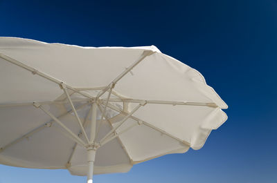 Low angle view of white umbrella against clear blue sky