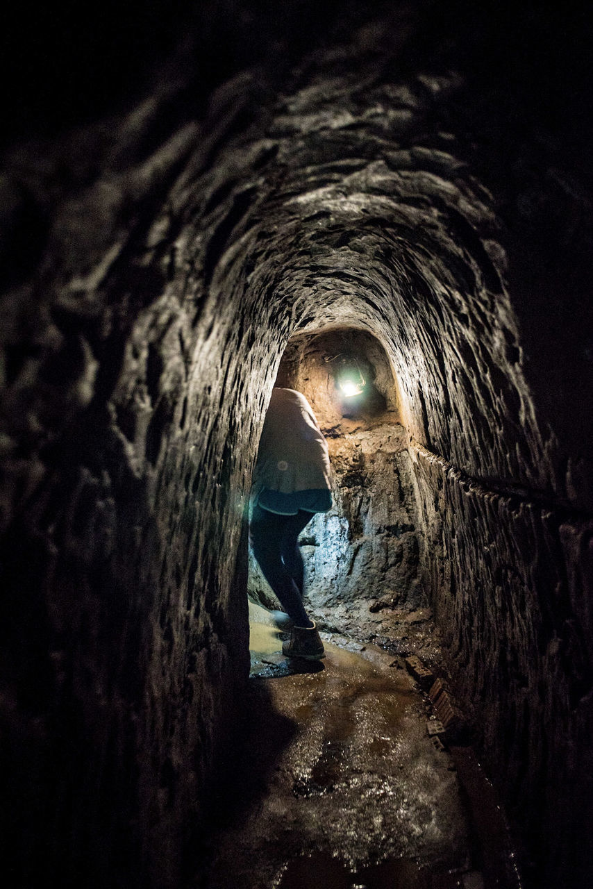 REAR VIEW OF MAN STANDING IN TUNNEL