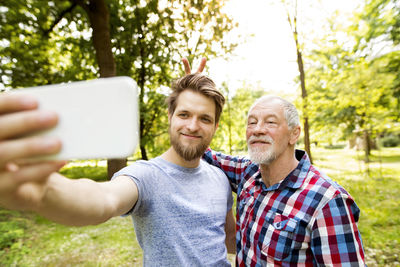 Portrait of senior father and his adult son taking selfie in a park