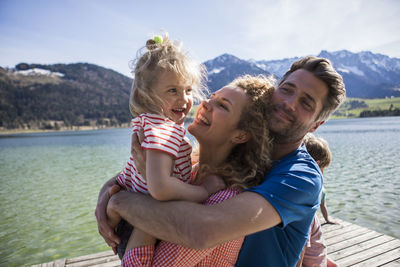 Austria, tyrol, walchsee, happy family hugging on a jetty at the lakeside