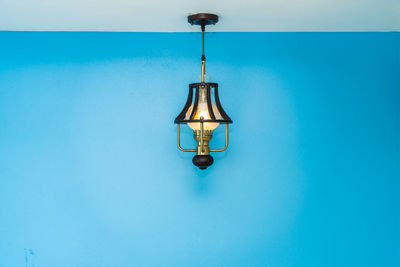 Close-up of illuminated electric lamp against blue wall