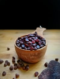 Close-up of chocolate chips in bowl on wooden table against black background
