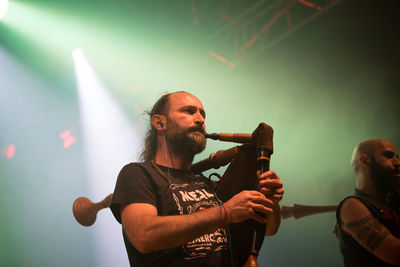 Young man with arms raised standing at music concert