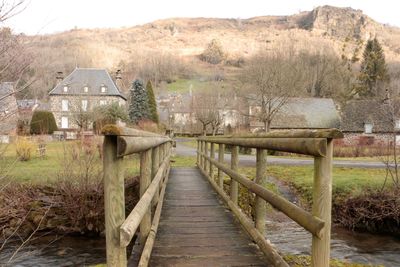 Wooden bridge over river amidst trees and buildings