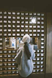 Rear view of woman looking through window